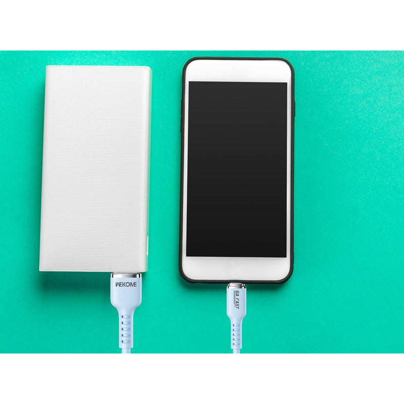 Un iPhone conectado a una batería portátil mediante el Cable De Datos 6A De Silicona Real Serie Tintt WDC-09A azul, en uso para transferir datos correctamente.